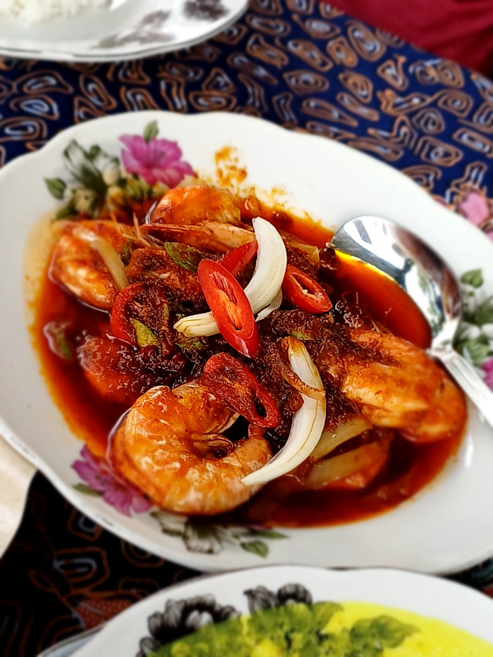 Prawns in red sambal sauce with sliced onion and chilli.