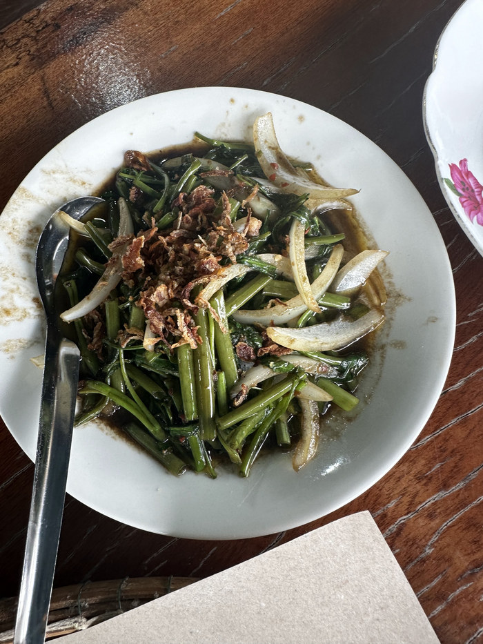 Stir-fried water spinach with onion and crispy garnish.